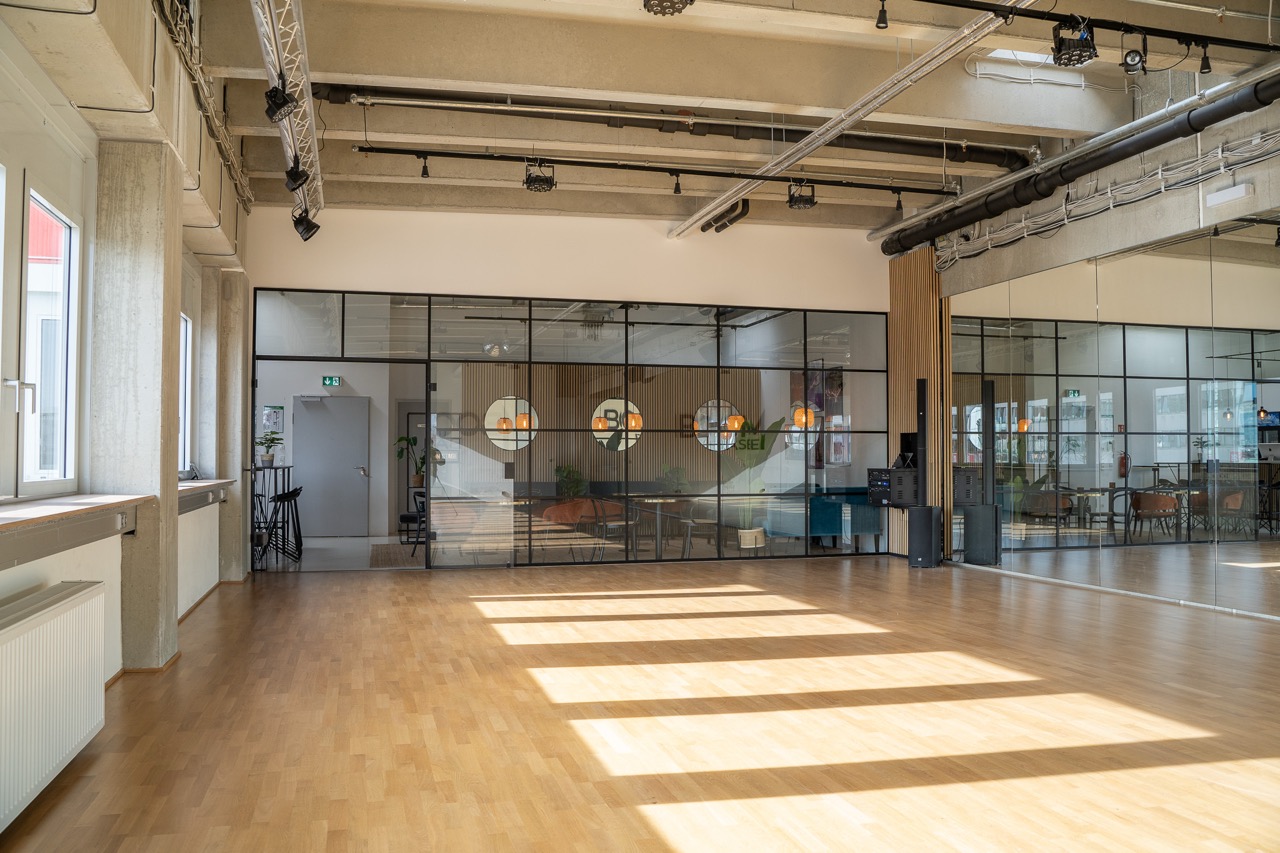 Blick in den hellen Tanzsaal von Boom Base mit Holzboden und Spiegeln