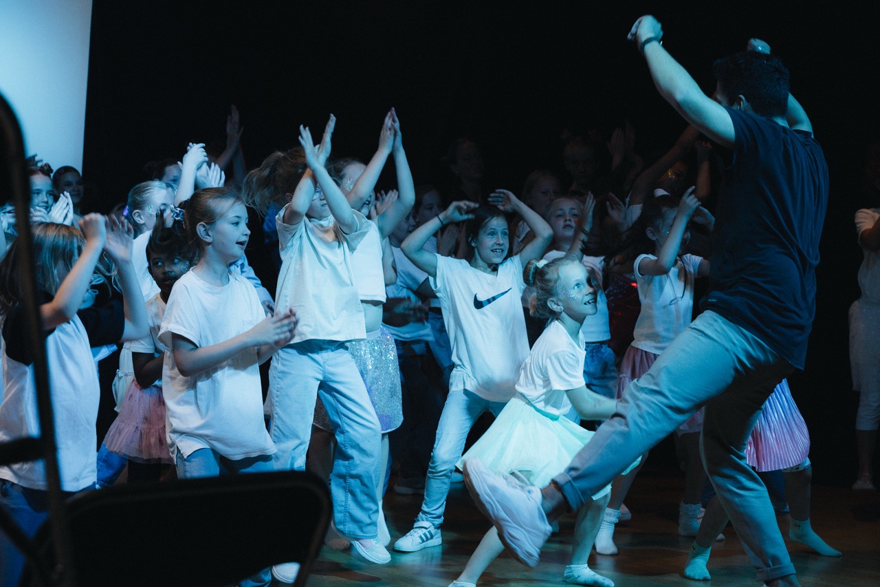 Kids-Gruppe von Boom Base in weißen Outfits bei einem Hip-Hop-Auftritt