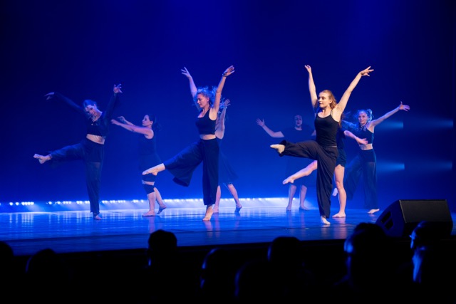 Teens zeigen Jazz Dance mit gestreckten Armen auf blau beleuchteter Bühne