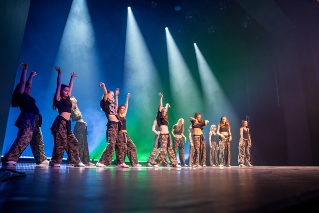 Teens tanzen Reggaeton auf der Bühne im Scheinwerferlicht